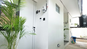 A clean, well-maintained hallway with a door, a wall-mounted intercom, and a water tank labeled "mpoin PLUS 550". - Studio 27 Sanur - Self Check-in (Denpasar)