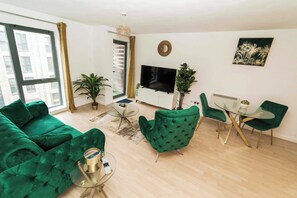 Una sala de estar moderna con un sofá verde, una mesa de centro de vidrio y un televisor de pantalla plana.