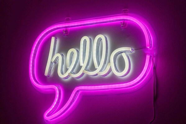 Un panneau lumineux au néon avec le mot « hello » inscrit dans une forme de bulle de dialogue.