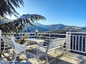Un espace extérieur aménagé avec des tables et des chaises, recouvert de neige, et offrant une vue sur un paysage montagneux.
