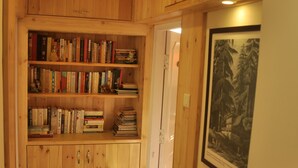 A wooden-paneled hallway with a bookshelf filled with books and a framed picture on the wall. - Vatsalyam Homestay (Shimla)