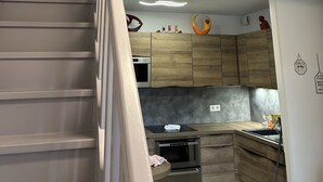 A modern kitchen with wooden cabinets, a built-in oven, and a stainless steel sink. - Le Cocon de la Garrigue (Agde)
