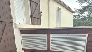 A wooden deck with a built-in bench and a white door. - Le Cocon de la Garrigue (Agde)