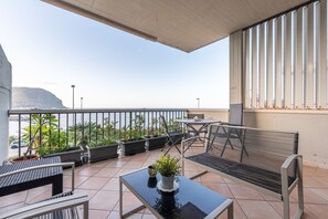 Un balcón con una mesa, sillas y plantas en macetas.