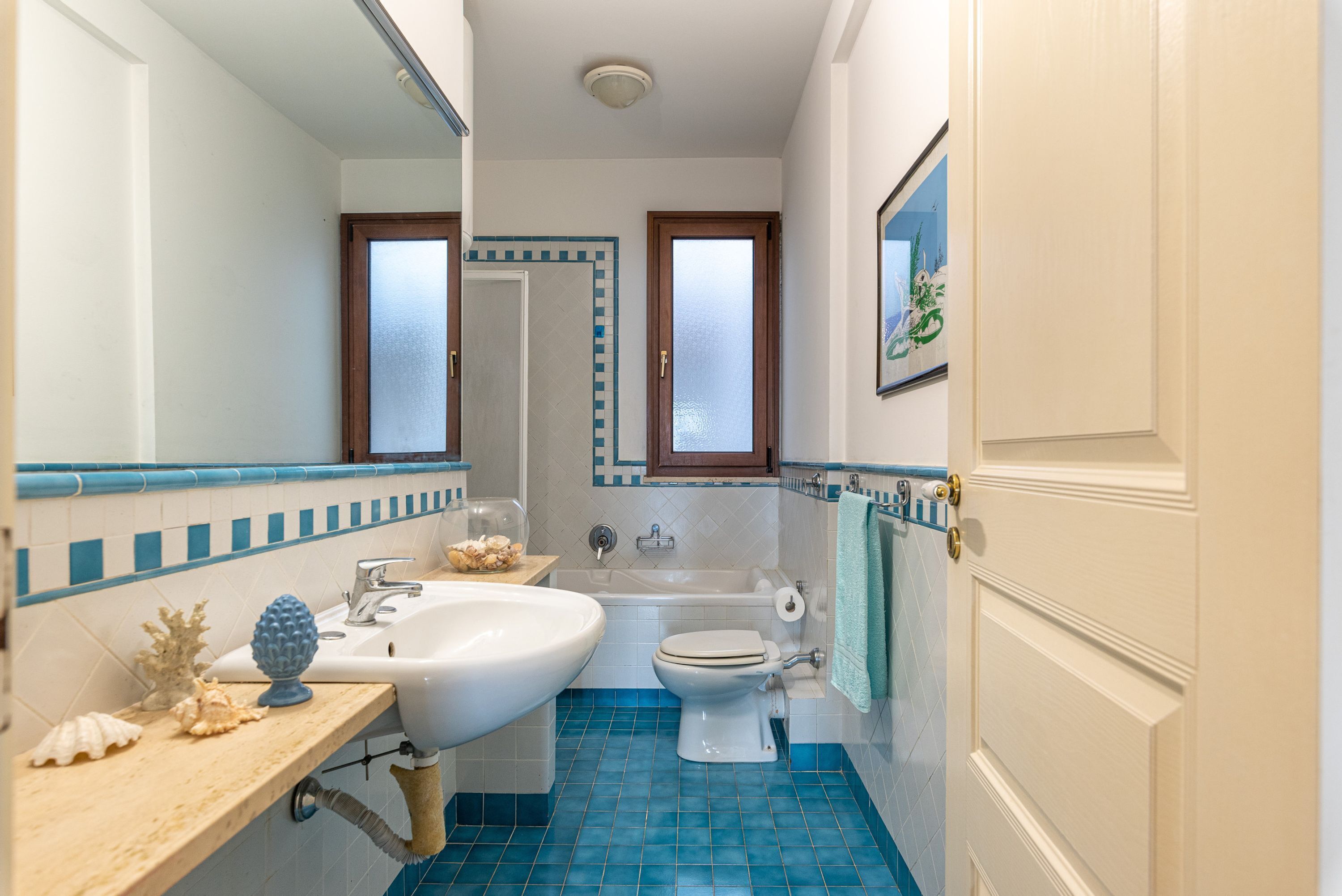Een badkamer met een wastafel, toilet, badkuip en een spiegel.