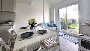 Una cocina moderna con armarios blancos, una mesa de comedor con platos y vasos, y un florero con flores.