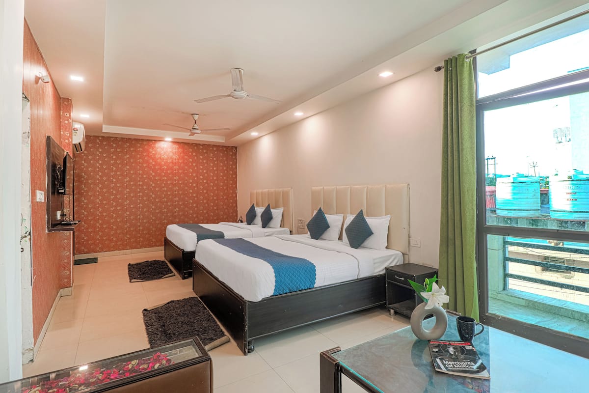 A hotel room with a bed, bedside tables, a TV, a window with curtains, and a view of the outside.