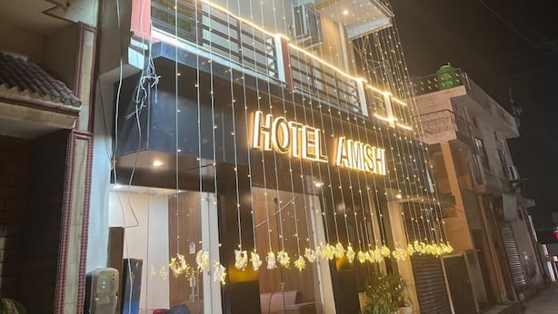 A hotel with a prominent sign reading "HOTEL AMSH" and a modern facade with string lights. - Hotel Amishi (Haridwar)