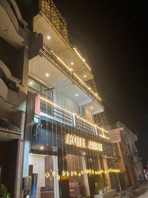A hotel with a prominent sign reading "HOTEL AMSH" and a modern facade with string lights. - Hotel Amishi (Haridwar)