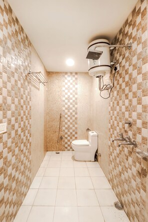 Egy fürdőszoba, melyben kockás mintájú csempe borítja a falat, zuhanyzó, WC és mosdókagyló található.