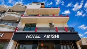 A hotel named 'HOTEL AMISHI' with a modern architectural design, featuring multiple balconies and a clear sky. - Hotel Amishi (Haridwar)