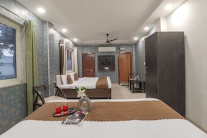A hotel room with a bed, a desk, a chair, a wardrobe, and a ceiling fan. - Hotel Amishi (Haridwar)