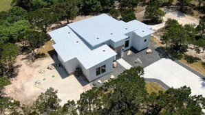 A modern two-story building with a flat roof, surrounded by trees.
