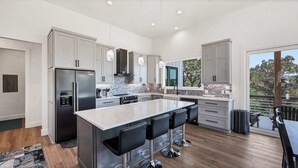 A modern kitchen with a large island, stainless steel appliances, and a view of the outdoors.