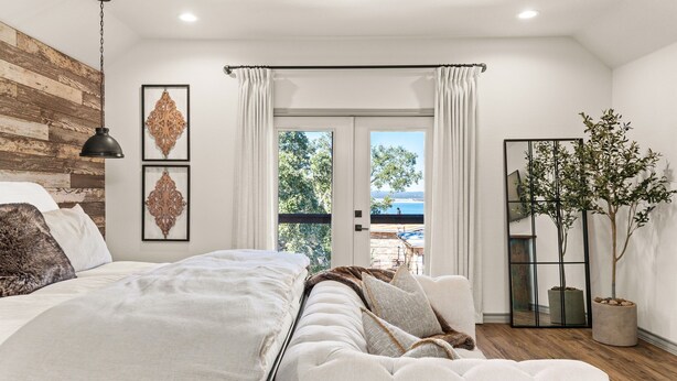 Ein Schlafzimmer mit einem großen Bett, einem Deckenventilator, Blick ins Freie und einem Blumentopf.
