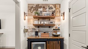 Eine Küchenzeile mit Holzböden, einer Kaffeestation und einem Kühlschrank.