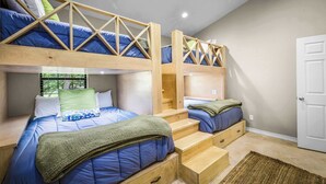 A bunk bed room with a wooden ladder, built-in drawers, and a view of greenery outside. - Enjoy the Full River | Fire Pit & Deck | Sleeps 12 (Seguin)