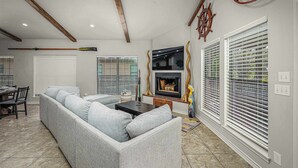 Una sala de estar con un sofá modular, una chimenea y un comedor con mesa y sillas.