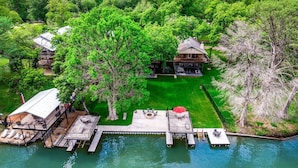 Una propiedad junto al lago con muelle, una casa grande y un césped bien cuidado.