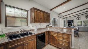 Una cocina con armarios de madera, lavavajillas y encimera de granito.