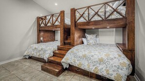 Un dormitorio con dos literas, cabeceros de madera y una escalera.