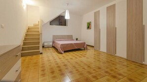Ein Schlafzimmer mit Bett, Treppe, Kleiderschrank und einer Pendelleuchte.