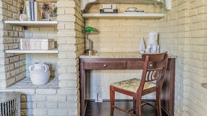 A study area with a wooden desk, chair, and shelving with books and decorative items. - Midtown Family Getaway w/ Game Room & Backyard (Columbus)