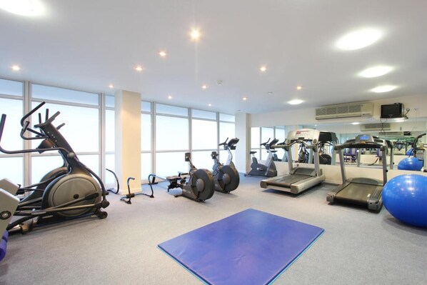 A gym with various exercise equipment including treadmills, stationary bikes, and elliptical machines.