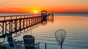 A pier extending into calm waters at sunset with chairs and a fishing net on the shore. - 3 bedroom 2.5 bath townhome (Rockport)