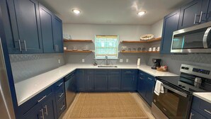 A modern kitchen with dark blue cabinets, stainless steel appliances, and a wooden floor. - 3 bedroom 2.5 bath townhome (Rockport)