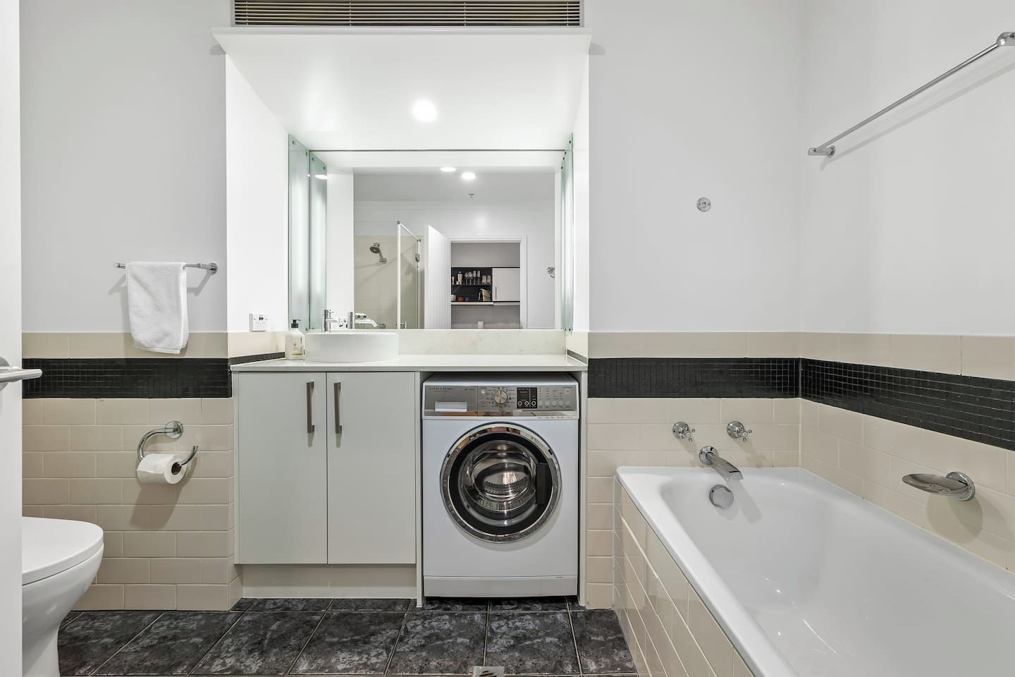 Ein modernes Badezimmer mit Waschmaschine, Badewanne und Toilette.