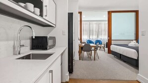 Une chambre d’hôtel moderne équipée d’une kitchenette, d’un coin repas et d’un lit.
