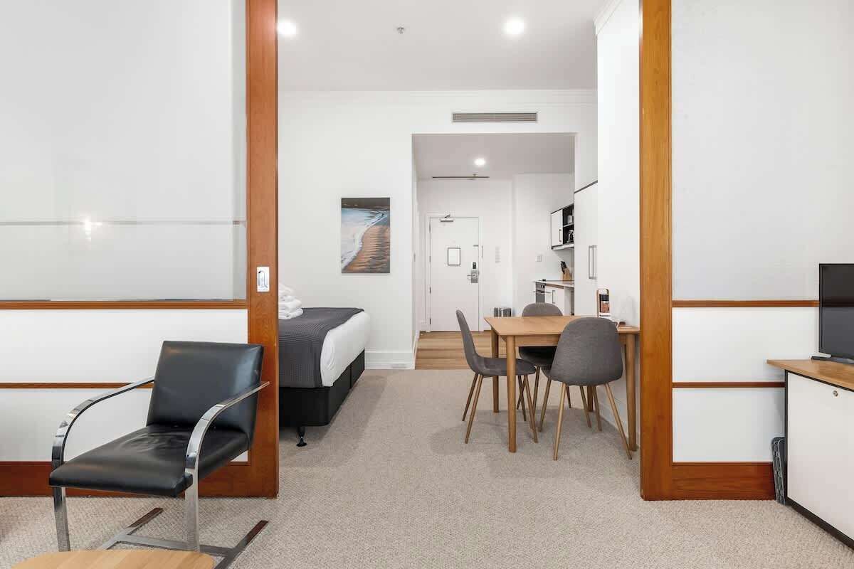 Una habitación de hotel con cama, escritorio, silla, mesa de comedor y televisor.