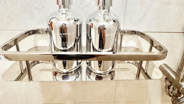 Dos botellas de champú sobre una bandeja de cromo en un baño.