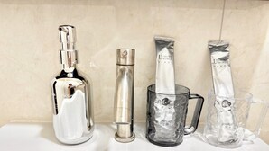 Un lavamanos con una botella, un tubo y dos vasos.