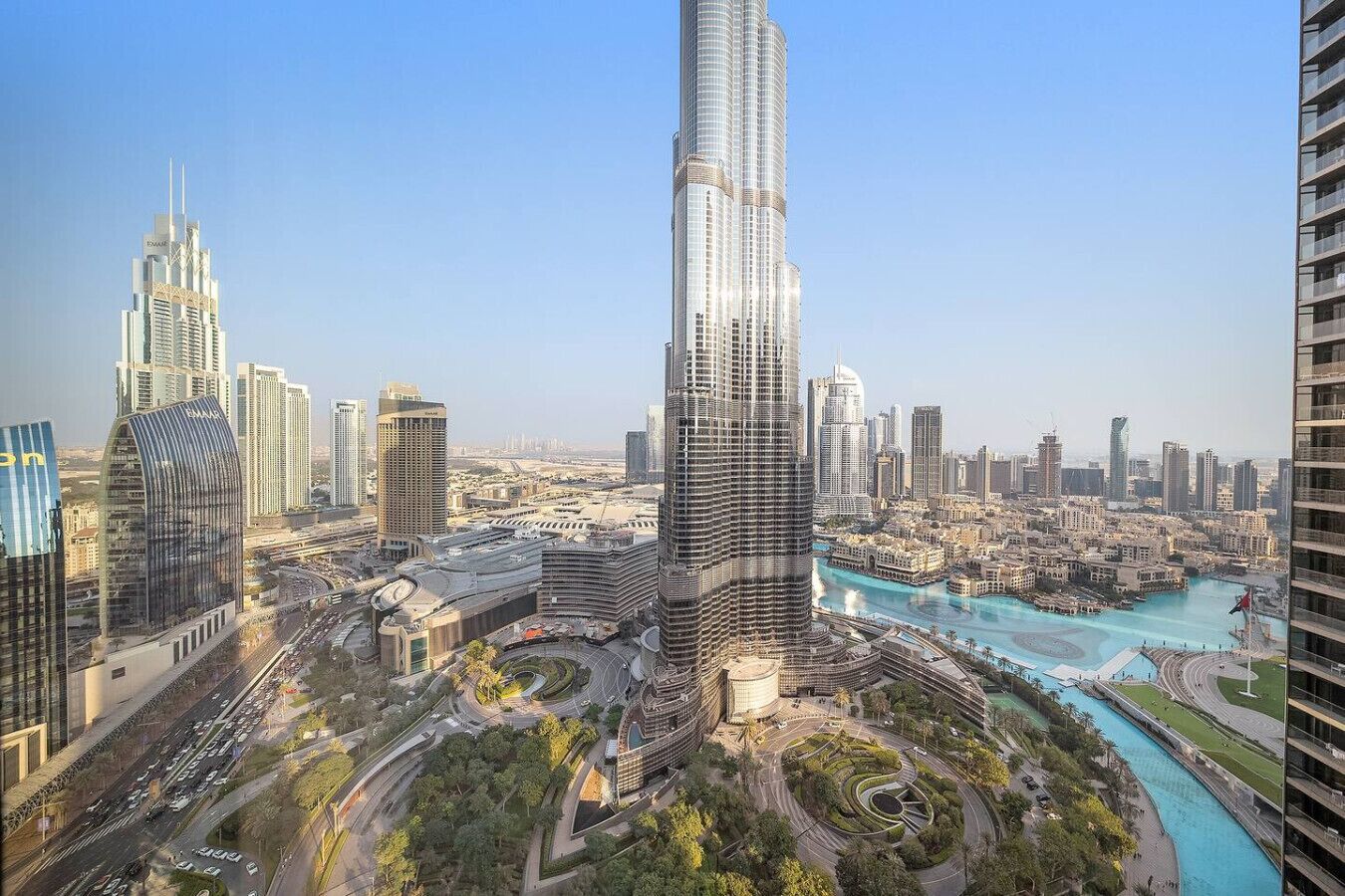 Een hoog gebouw met een opvallend gebogen gevel, omringd door andere moderne wolkenkrabbers en een rivier.