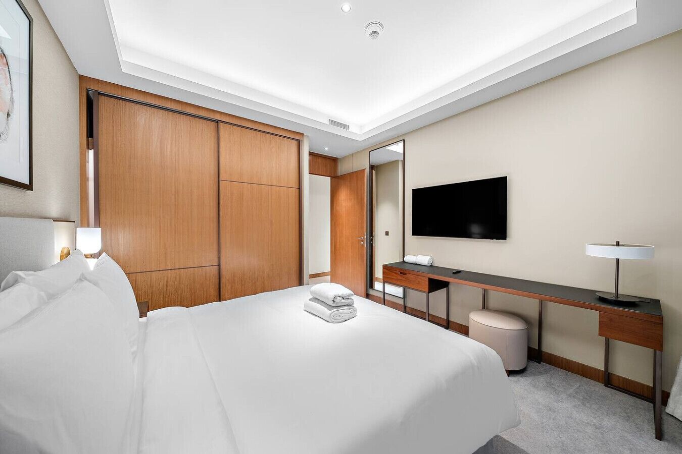 Une chambre d’hôtel moderne dotée d’un grand lit, d’un bureau, d’une télévision à écran plat et d’un dressing.