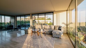 Amplia sala de estar con un sofá modular grande, dos mesas de centro y vista a un edificio a través de amplias ventanas.