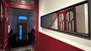A hallway with a red door, a black mat, and a large mirror on the wall. - # Le 7 # Nuitée torride, balnéo, tantra Mulhouse centre (Mulhouse)