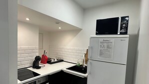 A compact kitchen with a black and white color scheme, featuring a built-in oven, a microwave, and a refrigerator. - # Le 7 # Nuitée torride, balnéo, tantra Mulhouse centre (Mulhouse)