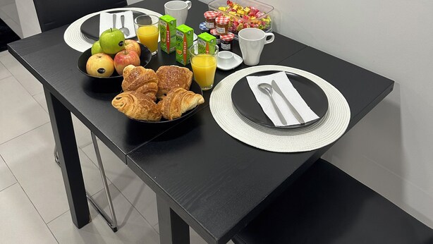 A breakfast table with croissants, apples, juice, and a fruit bowl. - # Le 7 # Nuitée torride, balnéo, tantra Mulhouse centre (Mulhouse)
