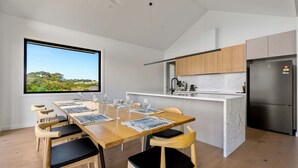 Una cocina moderna con refrigerador integrado, armarios de madera y un amplio ventanal con vistas a un paisaje pintoresco.