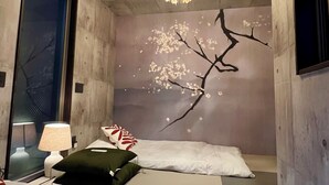 Ein Schlafzimmer mit einem Bett, einem Nachttisch, einer Lampe, einem Wandspiegel und einer Deckenleuchte.