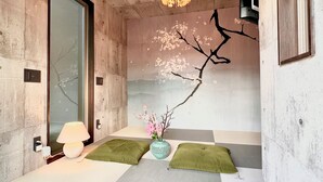 Ein Zimmer mit Tatami-Boden, einer hängenden Leuchte, einer Wand-Klimaanlage und einem Fenster mit Blick.