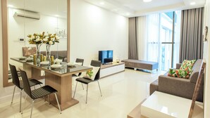 A modern living room with a dining area, a sofa, and a television. - Urban Oasis Apartment - Ha Do Centrosa (Ho Chi Minh City)