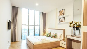 A modern hotel room with a large bed, a desk, and a city view. - Urban Oasis Apartment - Ha Do Centrosa (Ho Chi Minh City)