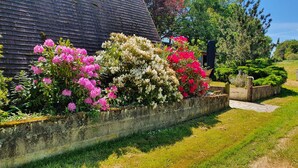A garden with a variety of flowering plants and a stone wall. - Rural 2 bedroom fully equiped Chalet (1 of 2) by lake near Chaillac sleeps max 6 (Chaillac)