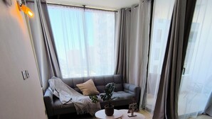 A modern living room with a grey sofa, a round coffee table, and a grey armchair.