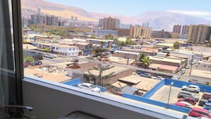 A balcony with a view of a cityscape, including buildings and mountains.