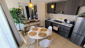 A modern kitchen with dark wood cabinets, a stainless steel refrigerator, and a dining area with a round table and white chairs.